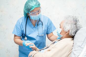 Nurse wearing PPE and talking to patient